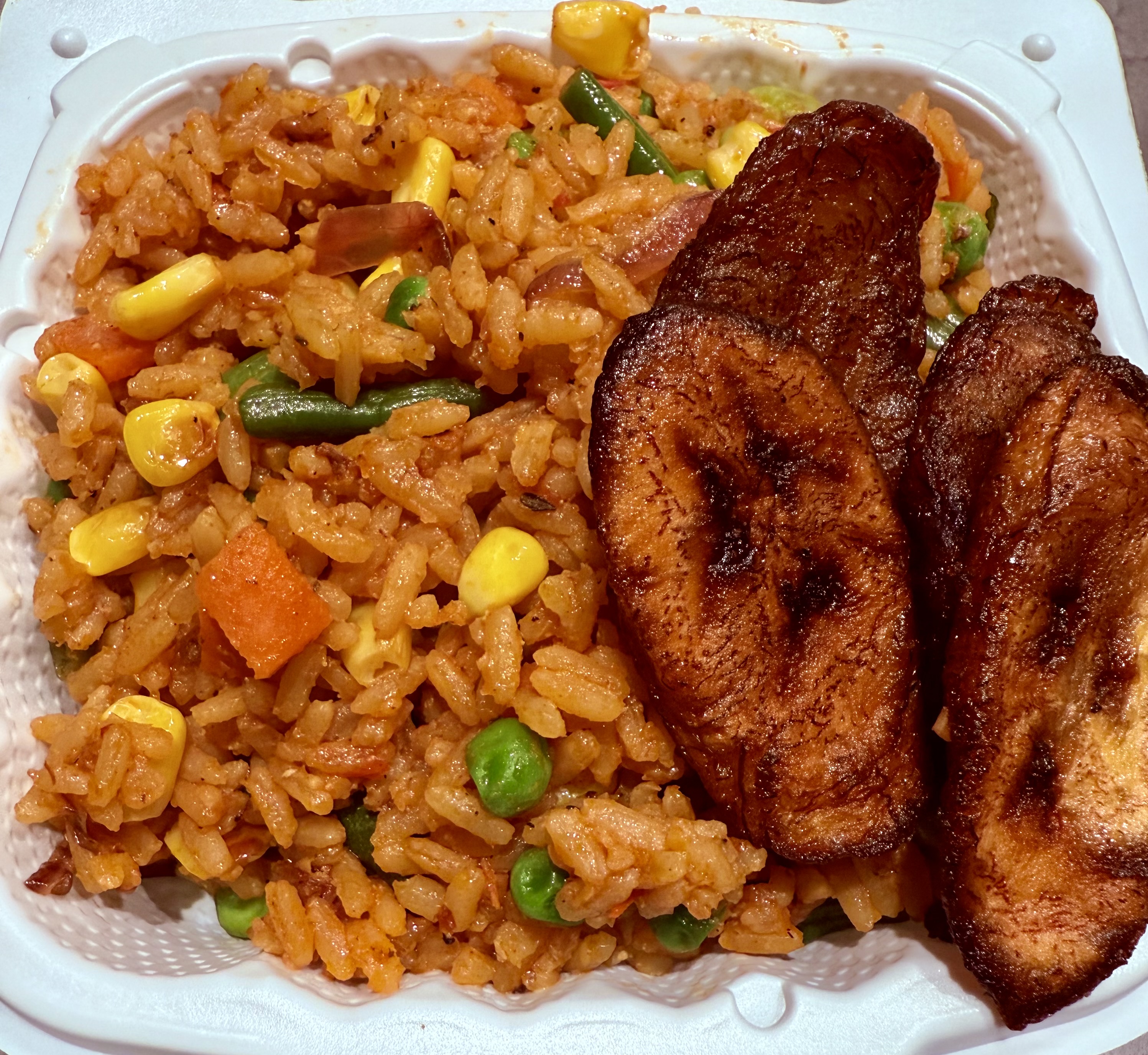 Vegetarian Jollof Rice with mixed vegetables, corn, peas and fried plantains